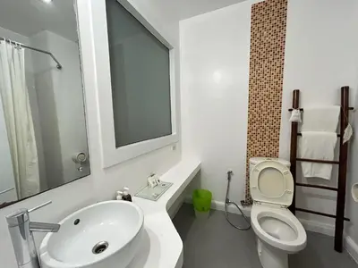 a white bathroom with a toilet and a sink at Benyada Lodge - Surin Beach in Surin Beach