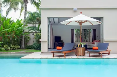 a swimming pool with two chairs and an umbrella at The Residence Resort in Bang Tao Beach