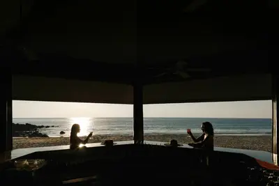 two women sitting at a table at the beach at The Surin Phuket in Surin Beach
