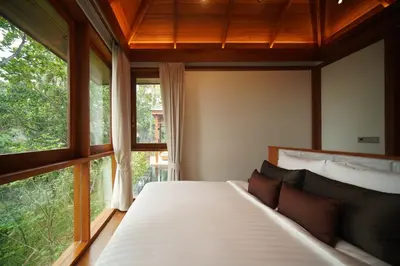 a bedroom with a bed and two windows at The Surin Phuket in Surin Beach