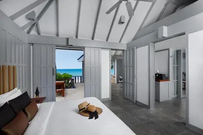 a bedroom with a bed and a view of the ocean at The Surin Phuket in Surin Beach