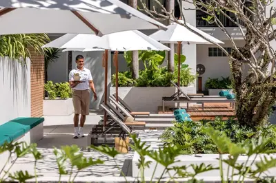 a man walking through a courtyard with umbrellas at OUTRIGGER Surin Beach Resort in Surin Beach