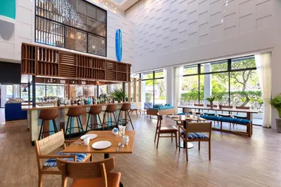a restaurant with tables and chairs and a bar at OUTRIGGER Surin Beach Resort in Surin Beach