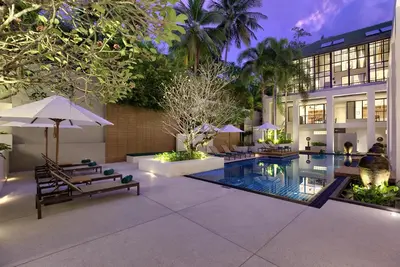 a resort with a pool and chairs and a building at OUTRIGGER Surin Beach Resort in Surin Beach