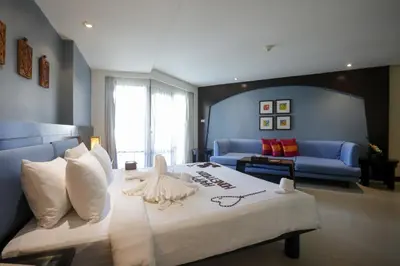 a bedroom with a large bed and a living room at Woraburi Phuket Resort & Spa - SHA Plus in Karon Beach
