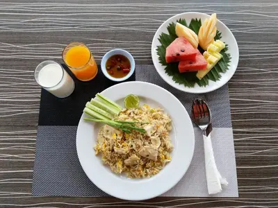 a table with two plates of food and fruit at Woraburi Phuket Resort & Spa - SHA Plus in Karon Beach