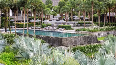 a pool with chairs and umbrellas in a resort at The Slate, Phuket in Nai Yang Beach