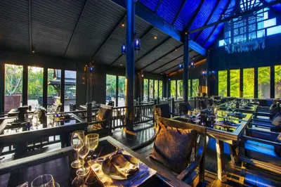 a restaurant with long tables and chairs and windows at The Slate, Phuket in Nai Yang Beach