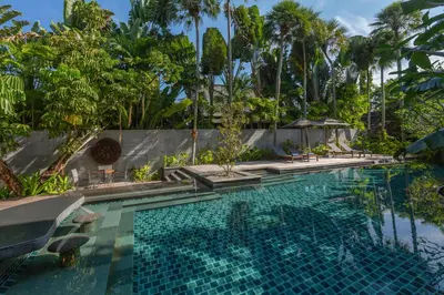 a pool at a resort with palm trees at The Slate, Phuket in Nai Yang Beach