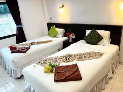 two beds in a hotel room with flowers on them at Lamai Apartment in Patong Beach