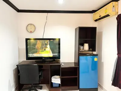 a room with a television and a desk with a chair and a clock at Lamai Apartment in Patong Beach