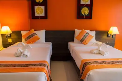two beds in a room with orange walls at Twin Hotel in Phuket Town