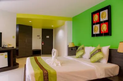 a bedroom with a large bed with a green wall at Twin Hotel in Phuket Town