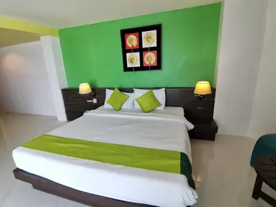 a bedroom with a large bed with a green wall at Twin Hotel in Phuket Town