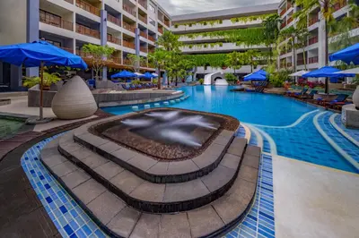 a swimming pool in a hotel with blue umbrellas at Deevana Plaza Phuket - SHA Extra Plus in Patong Beach