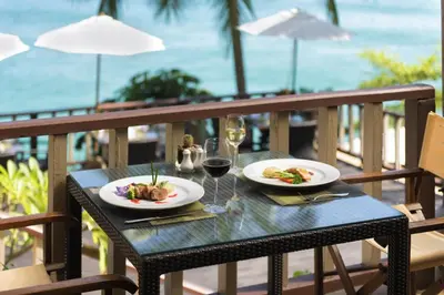 a table with two plates of food and a glass of wine at Centara Villas Phuket in Karon Beach