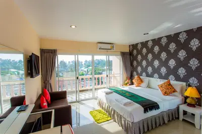 a hotel room with a bed and a balcony at Surin Sunset Hotel - SHA in Surin Beach