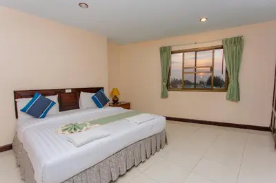 a bedroom with a large bed and a window at Surin Sunset Hotel - SHA in Surin Beach
