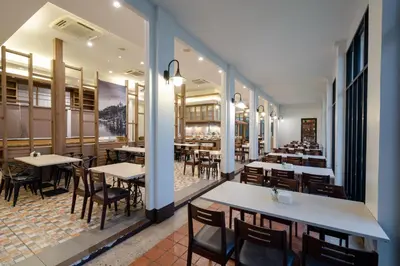a restaurant with tables and chairs in a room at Bhukitta Boutique Hotel Phuket Town in Phuket Town