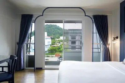 a bedroom with a bed and a large window at Bhukitta Boutique Hotel Phuket Town in Phuket Town