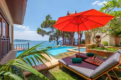 a red umbrella sitting next to a swimming pool at Diamond Cliff Resort & Spa, Patong Beach in Patong Beach
