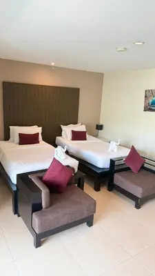 two beds and a chair in a room at Baramee Resortel in Patong Beach