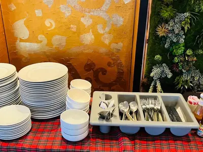 a table with white plates and forks and spoons at Baramee Resortel in Patong Beach