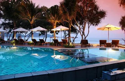 a swimming pool with chairs and umbrellas on the beach at Impiana Beachfront Resort Patong, Phuket in Patong Beach