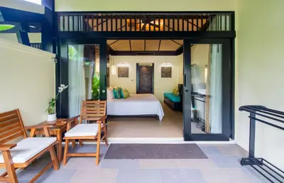 a room with a bed and chairs and a bedroom at Impiana Beachfront Resort Patong, Phuket in Patong Beach