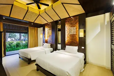 a bedroom with two beds and a ceiling fan at Impiana Beachfront Resort Patong, Phuket in Patong Beach