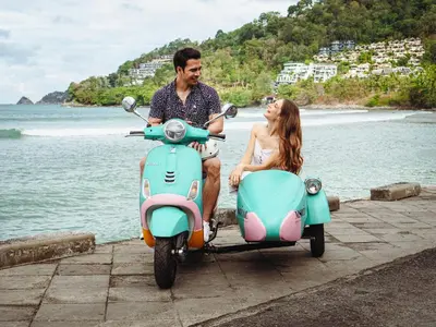 a man and a woman sitting on a scooter at M Social Hotel Phuket in Patong Beach