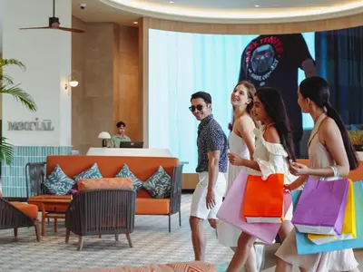a group of people walking through a lobby with shopping bags at M Social Hotel Phuket in Patong Beach