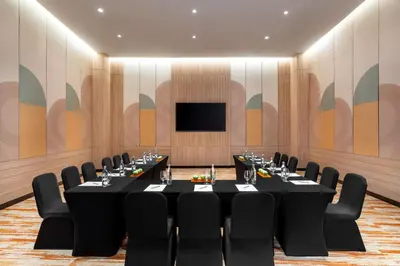 a conference room with a table and chairs and a screen at M Social Hotel Phuket in Patong Beach