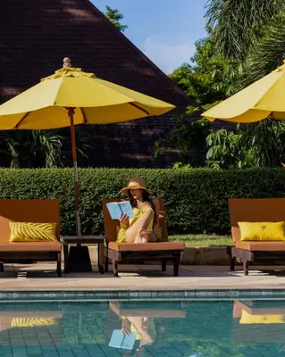 a woman sitting in a chair next to a pool at Pakasai Resort in Ao Nang Beach
