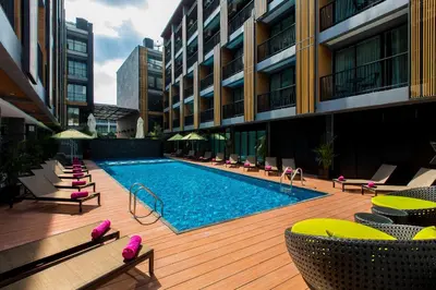 a swimming pool on a deck with chairs and a building at GLOW Ao Nang Krabi in Ao Nang Beach