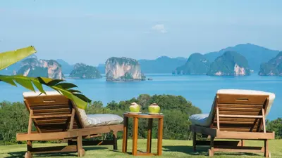 two chairs and a table with a view of the ocean at 9 Hornbills Tented Camp in Ko Yao Noi