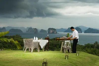 a man standing next to a table in a field at 9 Hornbills Tented Camp in Ko Yao Noi