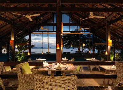 a restaurant with tables and chairs with a view of the ocean at 9 Hornbills Tented Camp in Ko Yao Noi