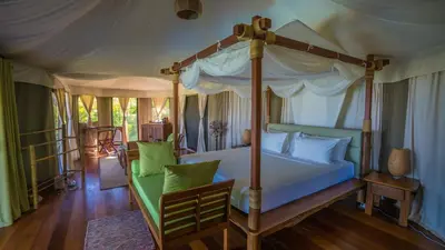 a bedroom with a canopy bed with green pillows at 9 Hornbills Tented Camp in Ko Yao Noi