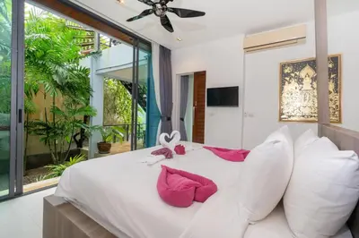 a bedroom with a white bed with pink pillows at Kamala Sea View-villa with private pool and maid in Kamala Beach