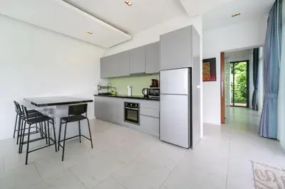 a kitchen with white appliances and a table and chairs at Kamala Sea View-villa with private pool and maid in Kamala Beach
