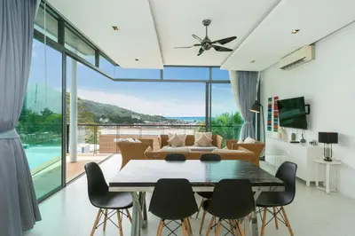 a dining room with a table and chairs and a couch at Kamala Sea View-villa with private pool and maid in Kamala Beach