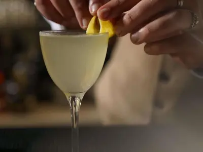 a person is putting a lemon into a drink at Navera Phuket - MGallery Collection in Surin Beach