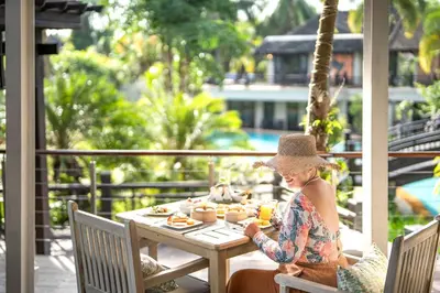 a woman sitting at a table with food on it at The Hotspring Beach Resort & Spa - SHA Extra Plus in Natai Beach