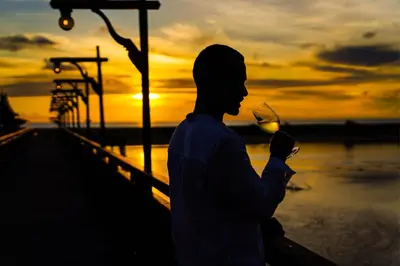 a man drinking a glass of wine at sunset at The Hotspring Beach Resort & Spa - SHA Extra Plus in Natai Beach