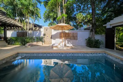 a pool with an umbrella and two chairs and a table at The Hotspring Beach Resort & Spa - SHA Extra Plus in Natai Beach