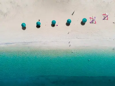 an aerial view of a beach with blue umbrellas at The Hotspring Beach Resort & Spa - SHA Extra Plus in Natai Beach