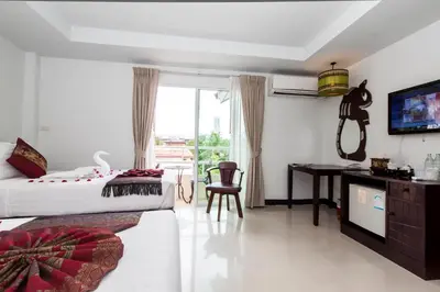 a bedroom with a bed and a desk and a television at Silver Resortel in Patong Beach