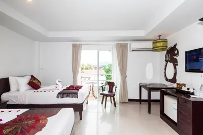 a bedroom with two beds and a desk and a television at Silver Resortel in Patong Beach