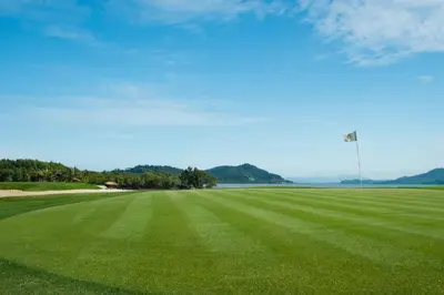 a golf course with a green field and a light pole at Mission Hills Phuket Golf Resort-SHA Extra Plus in Por Bay